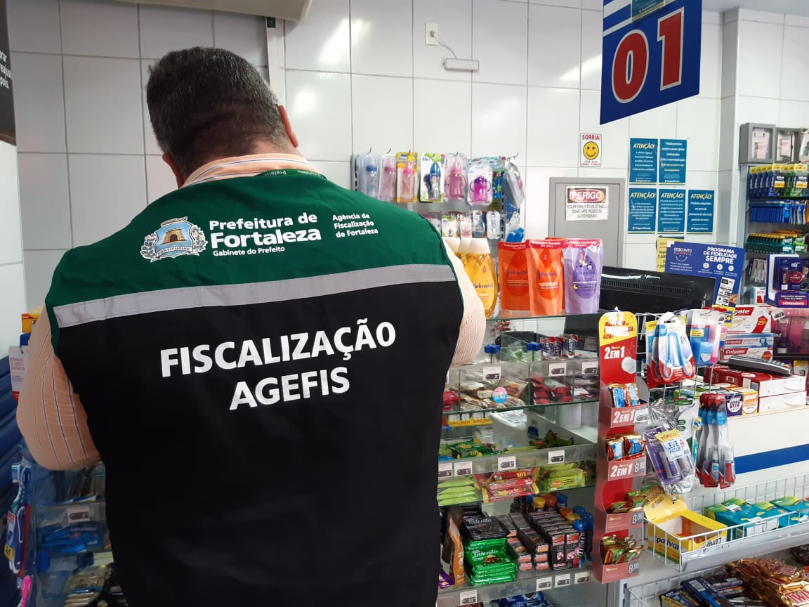 a imagem mostra um fiscal de costas dentro de uma farmácia